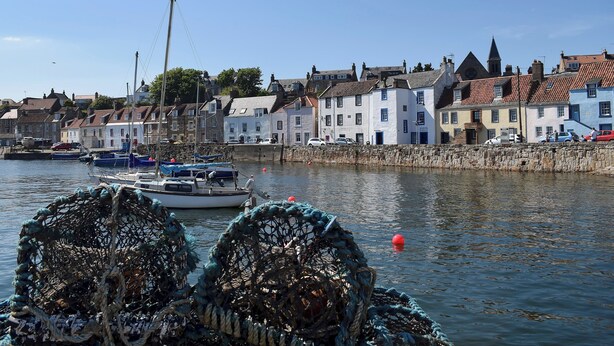 A harbor with boats, a stone wall, and buildings with red-tiled roofs. - 4 bedroom accommodation in St Monans, near Anstruther (St Monans, near Anstruther)