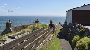 A coastal property with a wooden fence, stone wall, and a view of the sea. - 4 bedroom accommodation in St Monans, near Anstruther (St Monans, near Anstruther)