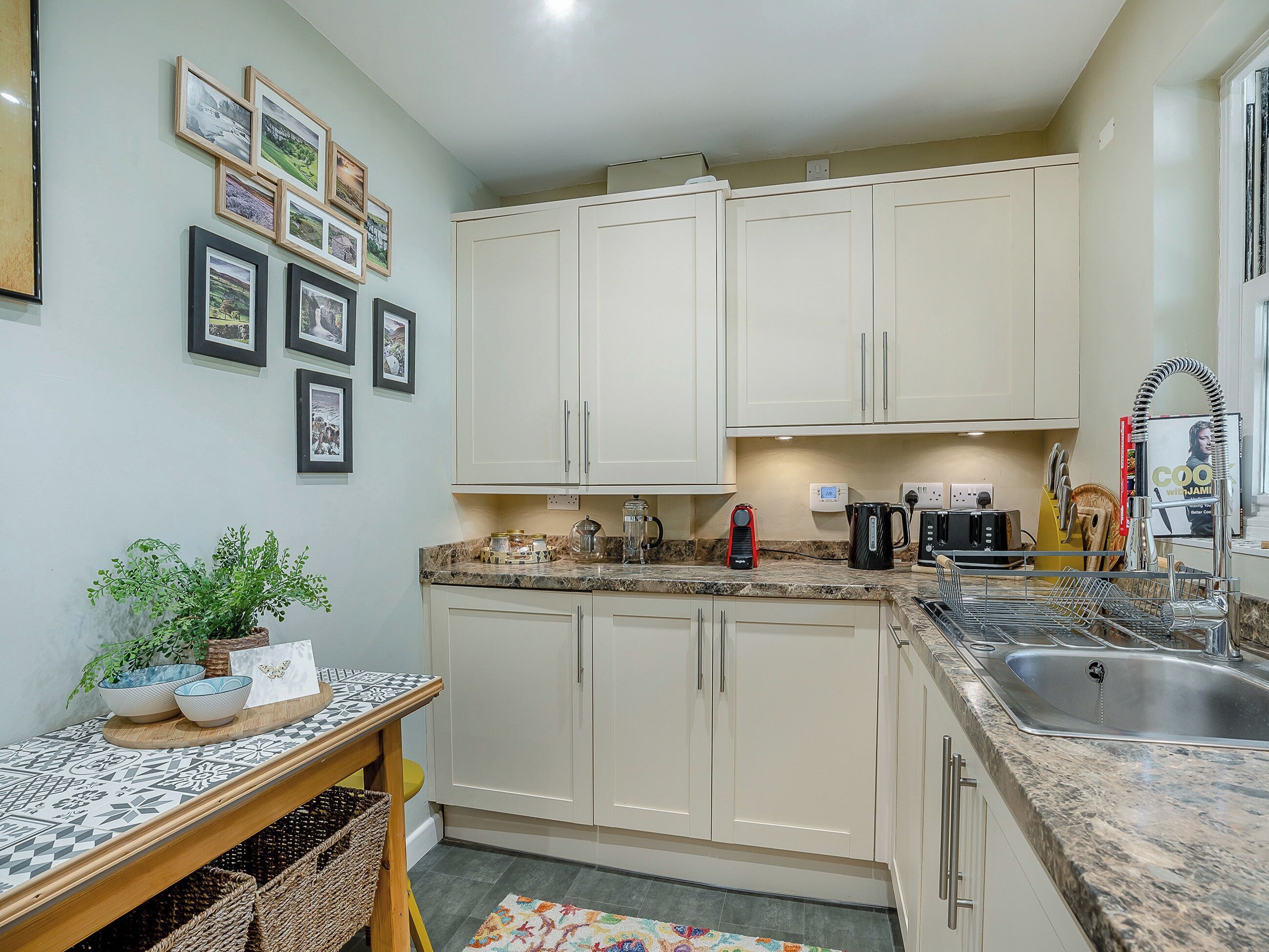 A compact kitchen with white cabinets, a granite countertop, a sink, and a coffee maker.