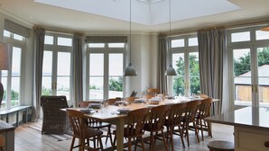 A dining room with a high ceiling, large windows, and a view of the outdoors. - 8 bedroom accommodation in Porthpean, near Charlestown (Porthpean, near Charlestown)
