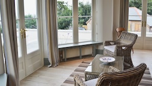 A room with a bench, wicker chairs, a table, and large windows with curtains. - 8 bedroom accommodation in Porthpean, near Charlestown (Porthpean, near Charlestown)