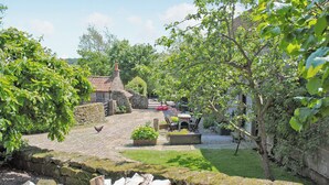 A rustic stone building with a tiled roof, surrounded by lush greenery and a stone wall. - THRESHING BARN - KZA (Glaisdale, near Whitby)