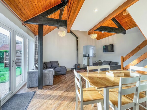 Un intérieur moderne avec un plafond en bois, un coin repas, un canapé et une cuisine.