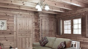 A cozy cabin interior with wooden walls, a sofa with plaid cushions, a coffee table with a magazine, and a window with blinds. - 2 bedroom accommodation in Killin, near Crianlarich (Killin, near Crianlarich)