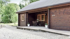A wooden cabin with a porch, two potted plants, and a sign reading "NAPLE". - 2 bedroom accommodation in Killin, near Crianlarich (Killin, near Crianlarich)