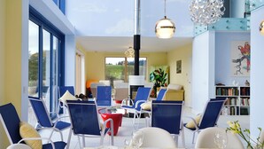 A dining area with a table set for four, chairs, a bookshelf, and a large window.