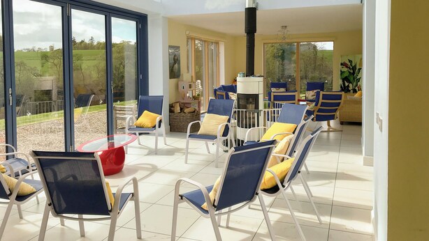 A spacious indoor area with large windows, a fireplace, and multiple seating arrangements.