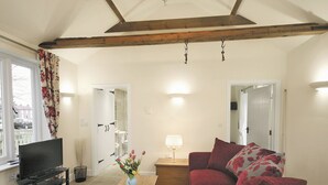 A living room with a TV, sofa, coffee table, and a vase of flowers. - 1 bedroom accommodation in Wainfleet St. Mary, near Skegness (Wainfleet St. Mary, near Skegness)