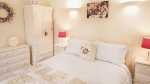 A bedroom with a bed, a wardrobe, a nightstand, a lamp, and a wall decoration. - 1 bedroom accommodation in Wainfleet St. Mary, near Skegness (Wainfleet St. Mary, near Skegness)