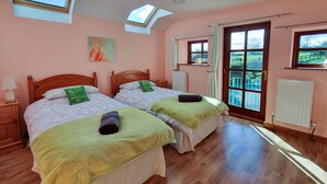 Een kamer met twee bedden, een dakvenster, een schilderij en uitzicht door een deur.