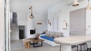 Un salon moderne avec un canapé, une table basse et des fauteuils. Un escalier mène à un autre niveau, et il y a une porte avec des rideaux.