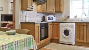 Une cuisine compacte avec des meubles en bois, un four à micro-ondes, un four traditionnel et un lave-linge.