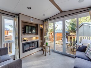 A living room with a fireplace, TV, and a balcony with outdoor furniture.