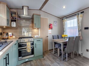 Une cuisine compacte équipée d’une cuisinière, d’un four et d’un coin repas avec des chaises et une table.