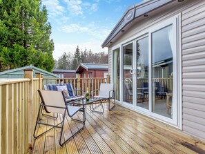Une terrasse dotée de mobilier d’extérieur, d’une porte-fenêtre coulissante et offrant une vue sur une zone boisée.