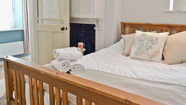 A bedroom with a bed, a wooden headboard, a white door, and a blue-tiled wall.