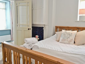 A bedroom with a bed, a wooden headboard, a white door, and a blue-tiled wall.