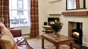 A living room with a sofa, a wooden coffee table, a fireplace, and a television. - 4 bedroom accommodation in Keswick (Keswick)