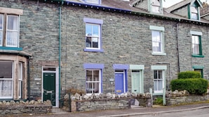 A row of stone houses with distinct window colors and a stone wall entrance. - 4 bedroom accommodation in Keswick (Keswick)