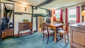 A dining area with a wooden table and chairs, a fireplace, and a staircase leading to another room. - 3 bedroom accommodation in Callow End, Worcester (Callow End, Worcester)