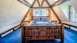 A bedroom with a wooden bed, two bedside tables, a window with curtains, and a sloped ceiling. - 3 bedroom accommodation in Callow End, Worcester (Callow End, Worcester)