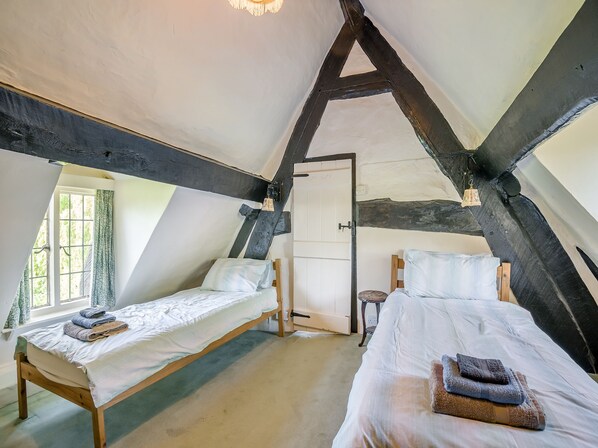 A bedroom with two beds, a sloped ceiling, and a door. - 3 bedroom accommodation in Callow End, Worcester (Callow End, Worcester)