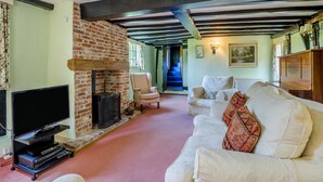 A living room with a fireplace, a television, a sofa, and a staircase leading to another room. - 3 bedroom accommodation in Callow End, Worcester (Callow End, Worcester)