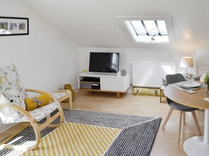 A modern living room with a TV, sofa, dining table, and a skylight. - 2 bedroom accommodation in Keswick (Keswick)