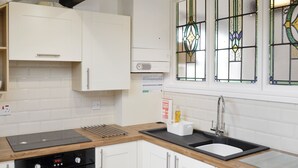 Eine moderne Küche mit weißen Schränken, einem schwarzen Backofen, einer Edelstahl-Spüle und einer Holz Arbeitsplatte.
