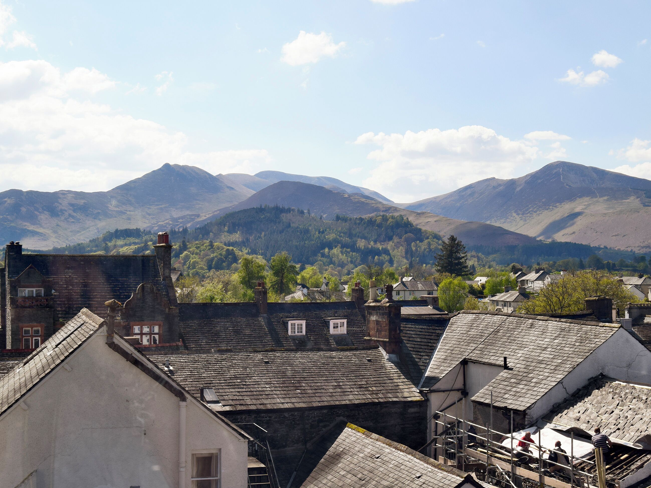 Eine Stadt mit traditioneller Architektur, im Hintergrund ein Gebirge und ein klarer Himmel.