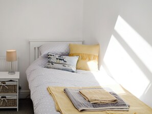 A neatly arranged bedroom with a bed, pillows, a bedside lamp, and a bedside table with a lamp.