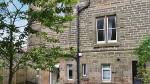 A stone building with multiple windows, a grassy yard, and a tree. - 3 bedroom accommodation in Alnmouth, Alnwick (Alnmouth, Alnwick)