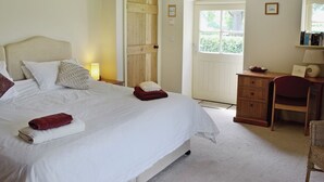 A bedroom with a bed, a desk, a chair, a door, and a window.