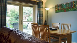 A room with a sofa, dining table, chairs, a lamp, and a painting on the wall.