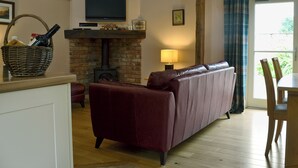 A living room with a fireplace, a sofa, a television, and a dining area with chairs.