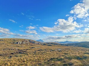 Un vaste paysage ouvert, avec des collines douces et un ciel bleu dégagé.