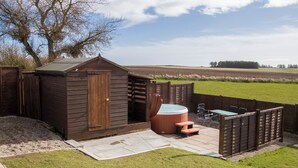 A wooden shed with a hot tub, a table, and chairs in a backyard. - 3 bedroom accommodation in Portmahomack, near Tain (Portmahomack, near Tain)