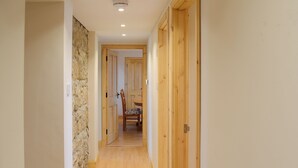 A narrow hallway with wooden doors, a stone wall on one side, and a wooden floor. - 3 bedroom accommodation in Portmahomack, near Tain (Portmahomack, near Tain)