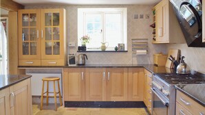 A kitchen with wooden cabinets, a stove, and a window with a view. - 1 bedroom accommodation in Brighstone, near Yarmouth (Brighstone, near Yarmouth)