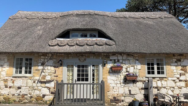 A stone building with a thatched roof, a small porch, and a sign reading 'Baxter Barn.' - 1 bedroom accommodation in Brighstone, near Yarmouth (Brighstone, near Yarmouth)