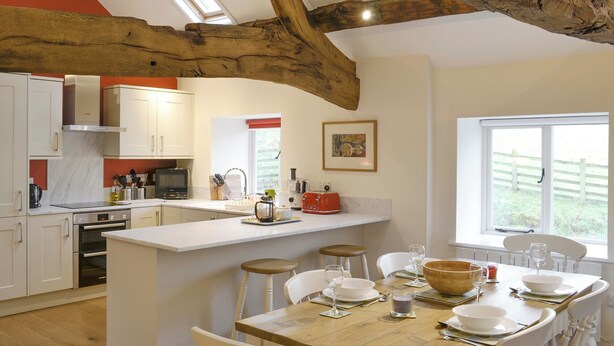 Una cocina moderna con armarios blancos, una isla de madera y un ventanal grande.