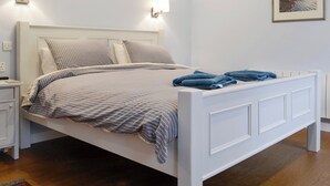 Una cama bien hecha con una colcha a rayas y almohadas, una mesita de noche con una lámpara y un cuadro en la pared.