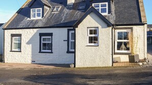 A two-story house with a gabled roof, white exterior walls, and multiple windows. - 2 bedroom accommodation in Portmahomack, near Tain (Portmahomack, near Tain)