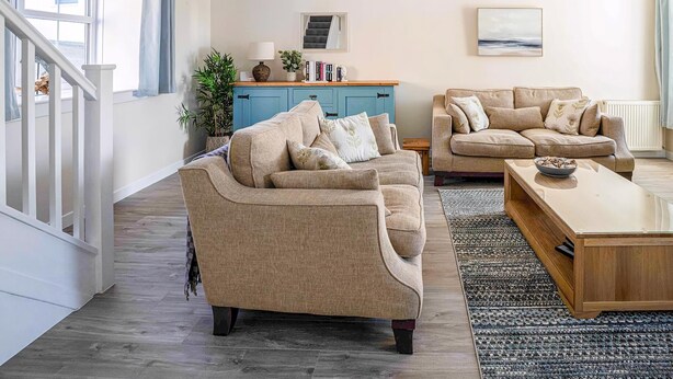 A living room with two sofas, a coffee table, a blue cabinet, and a staircase. - 2 bedroom accommodation in Portmahomack, near Tain (Portmahomack, near Tain)