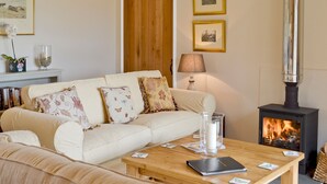 Ein gemütliches Wohnzimmer mit einem beigefarbenen Sofa, einem Holztisch, einem Kamin und gerahmten Bildern an der Wand.