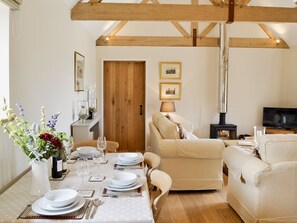 Una sala de estar acogedora con chimenea, un comedor con mesa dispuesta para cuatro personas y un sofá.
