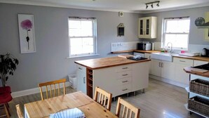 Een moderne keuken met witte kasten, een houten keukeneiland en een eethoek met een houten tafel en stoelen.