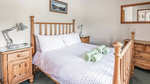 Un letto rifatto con cura, con una coperta a motivi decorativi, una testiera in legno, due lampade ai lati del letto, un comodino in legno e uno specchio sulla parete.