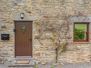 Un edificio de piedra con una puerta marrón, una ventana y un buzón.