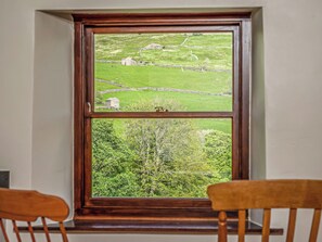 Una ventana con vistas a un paisaje verde, que incluye campos y árboles.